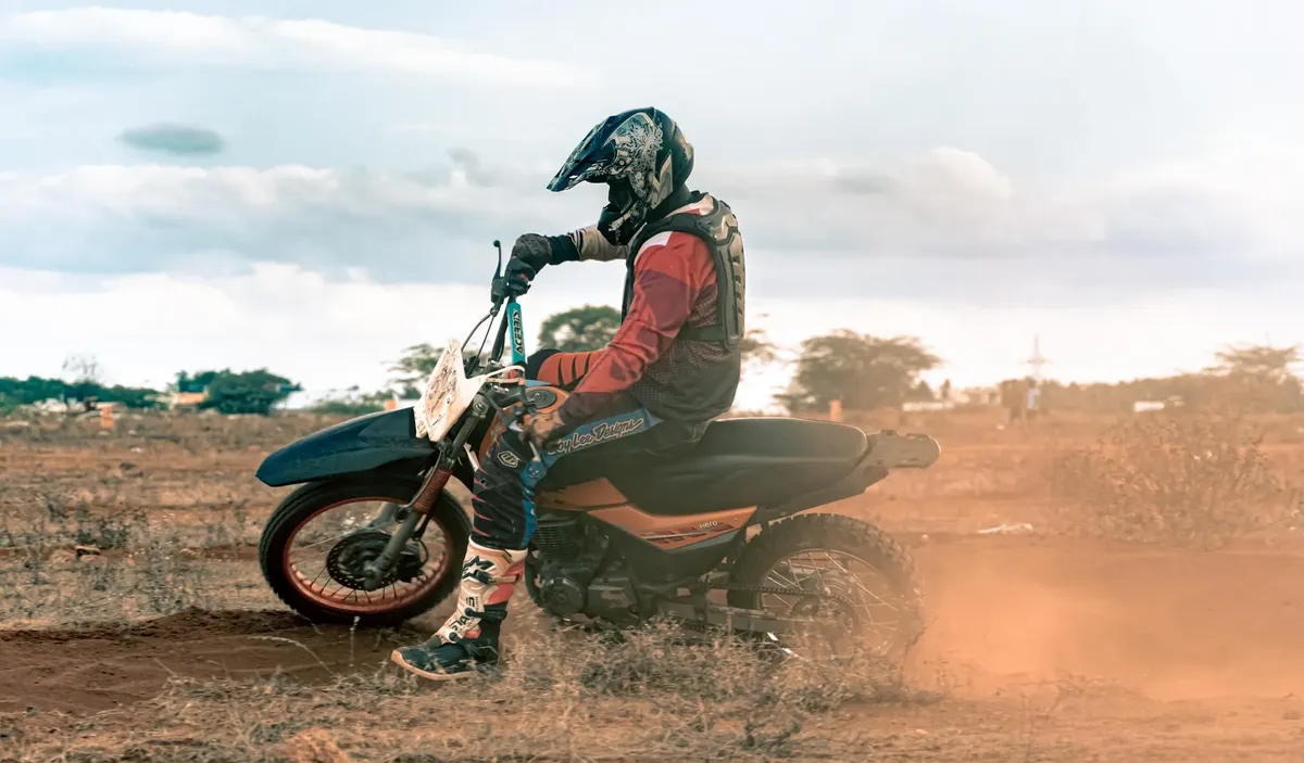 Motorcyclist riding a dirt bike on a rugged outdoor trail during the day.