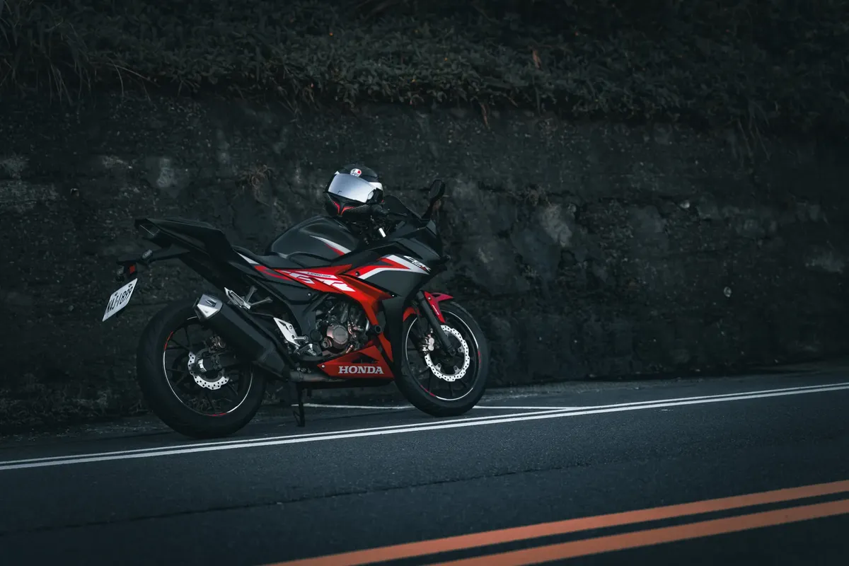 A red Honda motorbike parked on a quiet roadside, perfect for travel enthusiasts.